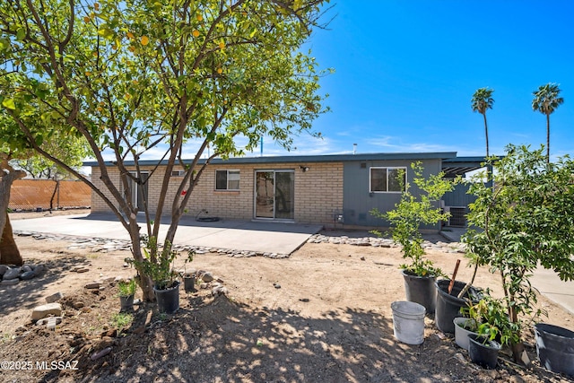 rear view of property with brick siding, fence, and a patio