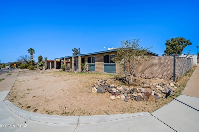 ranch-style house with concrete driveway, brick siding, and fence