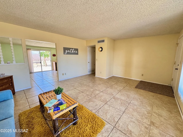 unfurnished living room featuring visible vents, baseboards, a textured ceiling, and tile patterned flooring