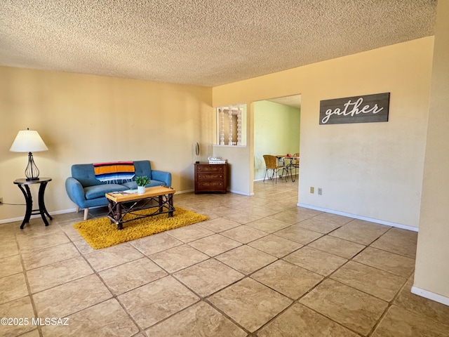 living area with baseboards, tile patterned flooring, and a textured ceiling