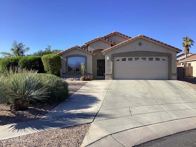 mediterranean / spanish-style house with driveway, an attached garage, a tiled roof, and stucco siding