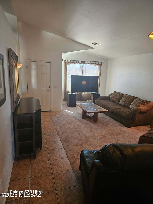 tiled living room with carpet floors, vaulted ceiling, and visible vents