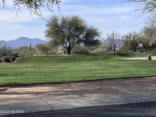surrounding community with community basketball court, a mountain view, and a yard