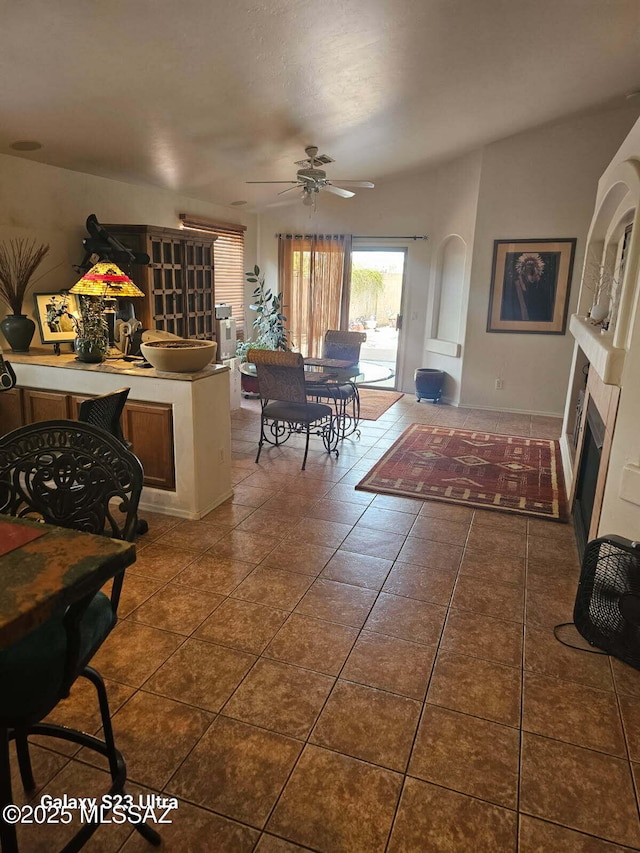 interior space with dark tile patterned floors, a glass covered fireplace, and ceiling fan