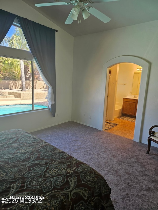 bedroom featuring arched walkways, carpet floors, ensuite bathroom, and a ceiling fan