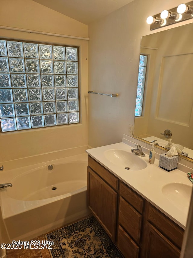 bathroom with a wealth of natural light, a sink, a garden tub, and tile patterned floors