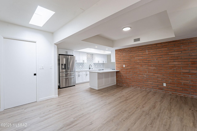 kitchen with visible vents, stainless steel refrigerator with ice dispenser, light wood-style floors, and a skylight