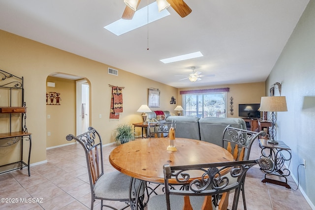 dining area featuring arched walkways, visible vents, a skylight, and a ceiling fan