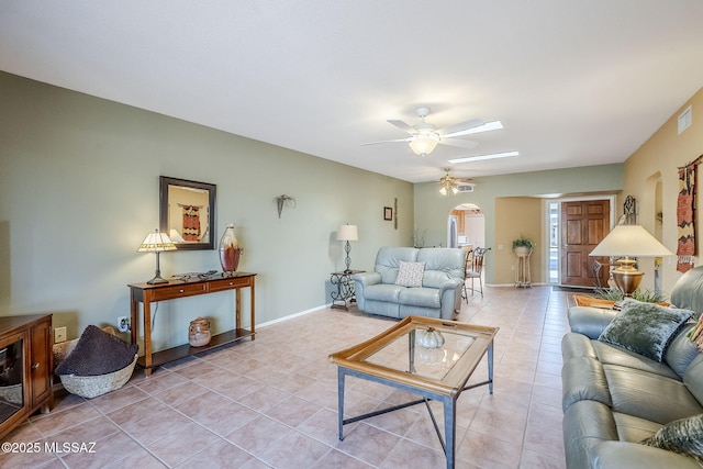 living area featuring visible vents, baseboards, ceiling fan, light tile patterned flooring, and arched walkways