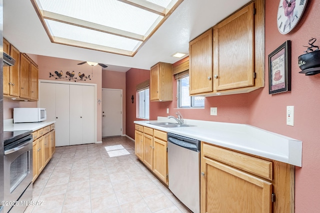 kitchen featuring light tile patterned floors, a ceiling fan, a sink, light countertops, and appliances with stainless steel finishes