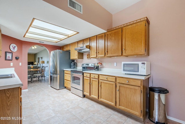 kitchen featuring visible vents, under cabinet range hood, light countertops, appliances with stainless steel finishes, and arched walkways