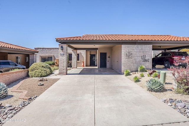 view of front facade featuring an attached carport, a tiled roof, and concrete driveway