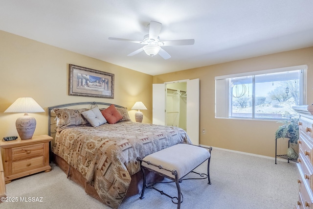 bedroom featuring a closet, baseboards, light colored carpet, ceiling fan, and a spacious closet