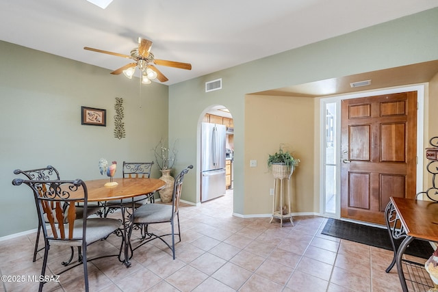 dining space with arched walkways, visible vents, ceiling fan, and light tile patterned floors