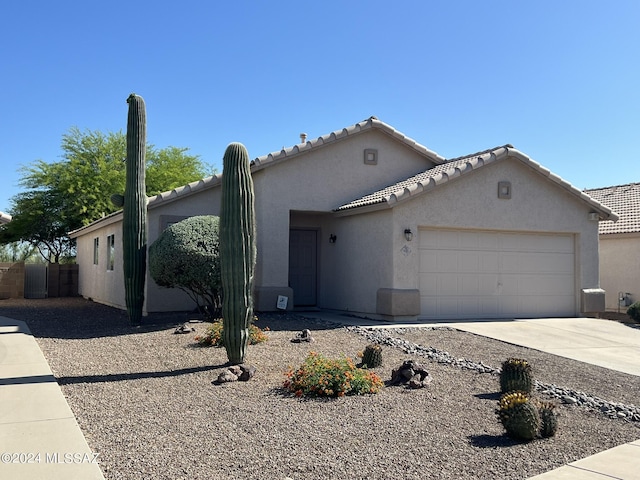 view of front of house featuring a tiled roof, a garage, driveway, and stucco siding
