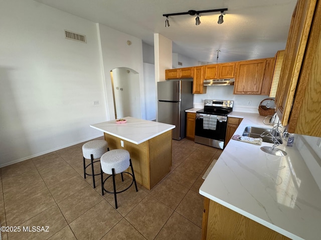 kitchen featuring visible vents, under cabinet range hood, arched walkways, appliances with stainless steel finishes, and lofted ceiling