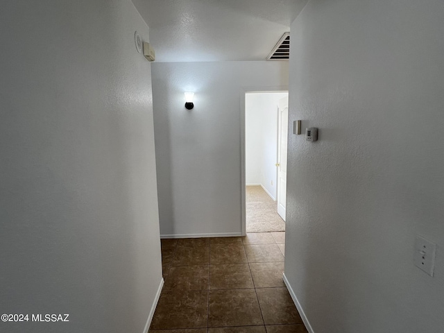 corridor featuring tile patterned flooring, visible vents, and baseboards