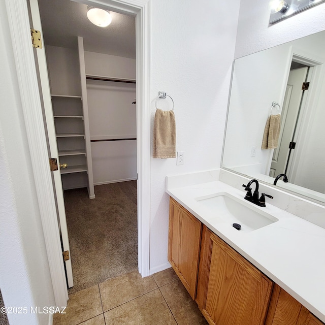 bathroom featuring tile patterned flooring, a spacious closet, and vanity