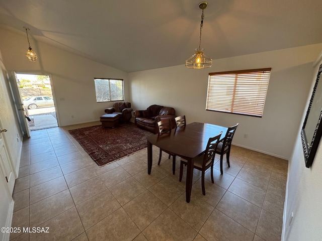 tiled dining room with vaulted ceiling and baseboards
