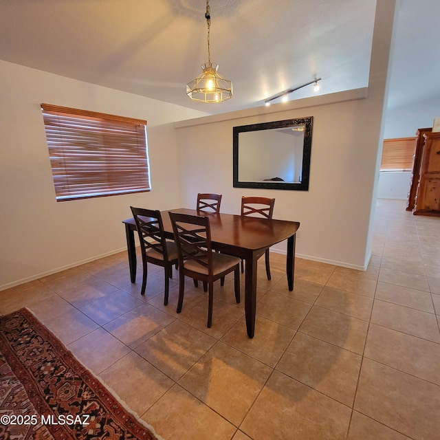 tiled dining room featuring track lighting and baseboards