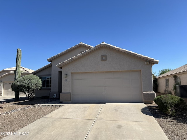 single story home with concrete driveway, a tiled roof, central AC unit, and stucco siding