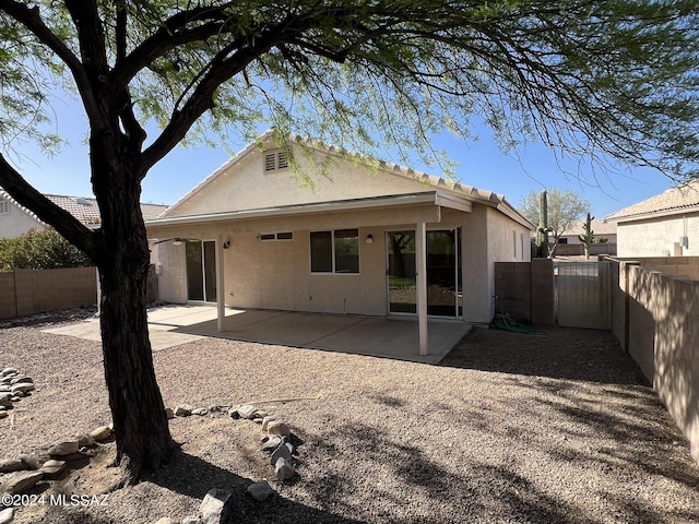 rear view of property featuring stucco siding, a patio, a fenced backyard, and a gate