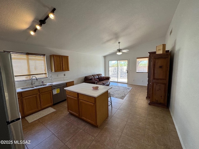kitchen featuring open floor plan, light countertops, appliances with stainless steel finishes, a textured ceiling, and a sink