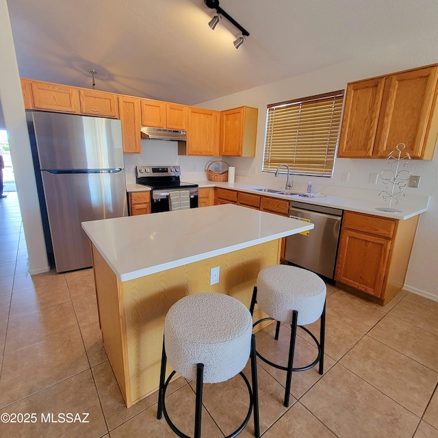 kitchen featuring a sink, light tile patterned floors, under cabinet range hood, and stainless steel appliances