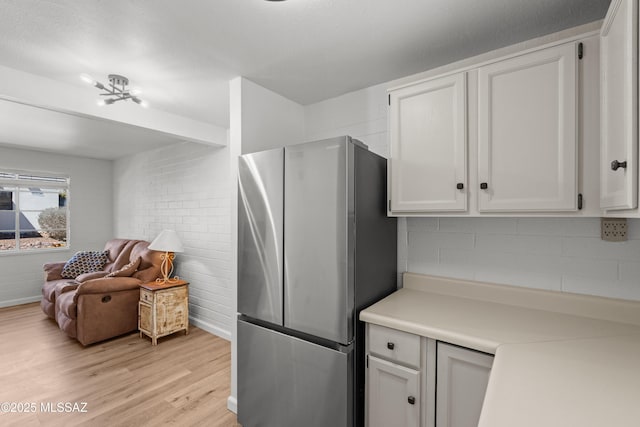 207 S Paseo Tierra Unit A, Green Valley, AZ 85614 - kitchen featuring freestanding refrigerator, light wood finished floors, white cabinets, light countertops, and baseboards