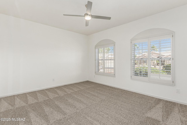 empty room with carpet flooring, baseboards, and a ceiling fan