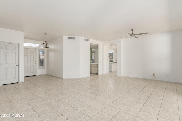 empty room featuring visible vents, arched walkways, baseboards, and ceiling fan