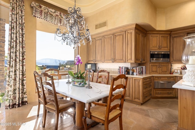 dining area featuring visible vents, a notable chandelier, and a high ceiling