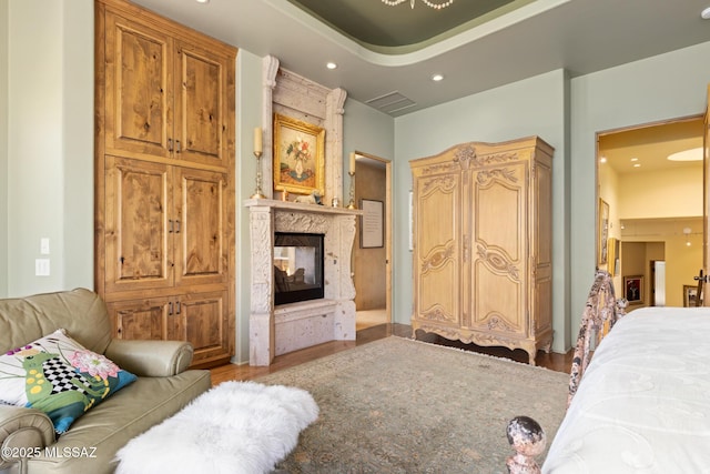 bedroom featuring a high end fireplace, recessed lighting, and wood finished floors