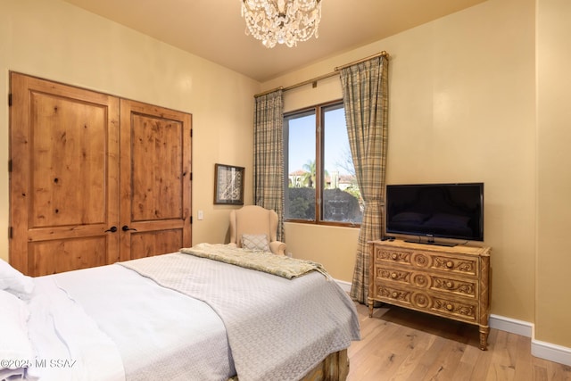 bedroom with a notable chandelier, baseboards, and light wood-type flooring