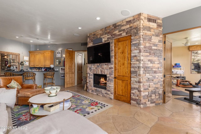 living room with visible vents, stone finish floor, a fireplace, and recessed lighting