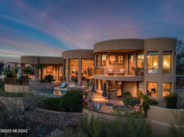 rear view of house with a balcony, stucco siding, and a patio area