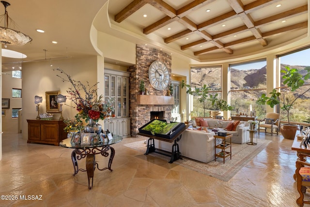 living room with a towering ceiling, coffered ceiling, beamed ceiling, and a stone fireplace