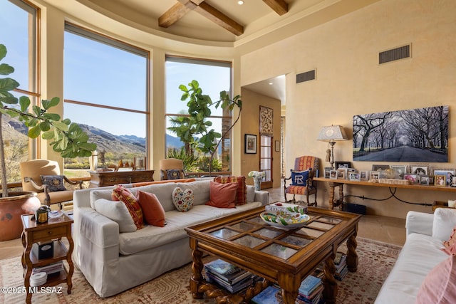 living room featuring beamed ceiling, visible vents, a high ceiling, and a mountain view
