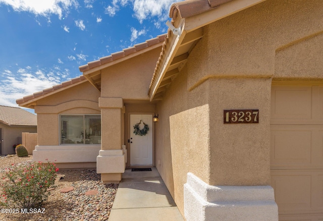 view of exterior entry featuring stucco siding and a tiled roof