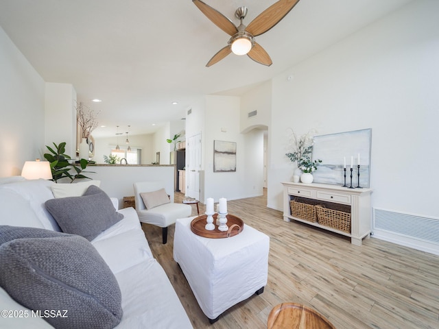 living room with visible vents, arched walkways, light wood-style floors, and ceiling fan