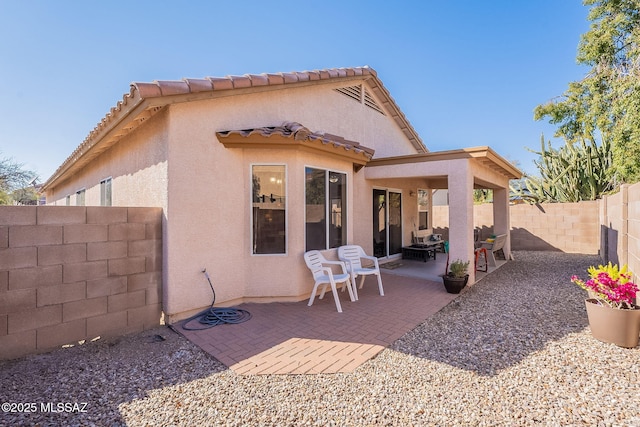 back of house with a fenced backyard, stucco siding, and a patio