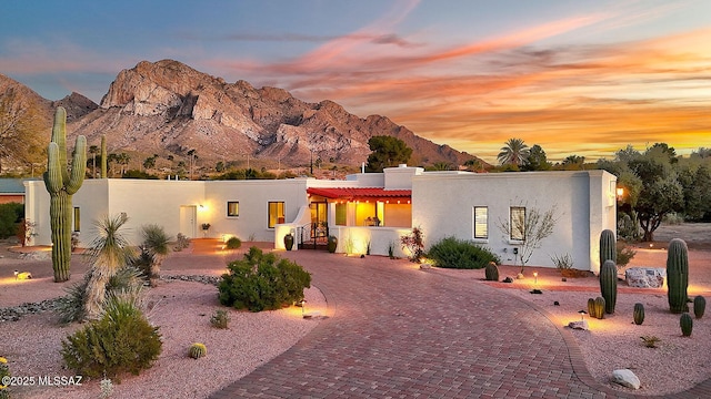 pueblo-style house featuring stucco siding, a chimney, a mountain view, and curved driveway