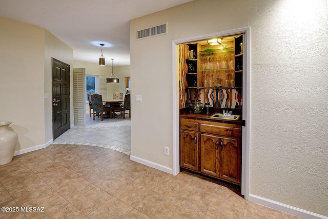 bar with a sink, baseboards, bar, and visible vents
