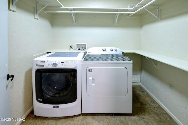 washroom featuring baseboards, separate washer and dryer, visible vents, and laundry area