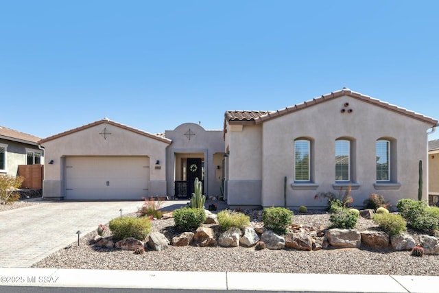 mediterranean / spanish house featuring stucco siding, driveway, central AC unit, a tile roof, and a garage