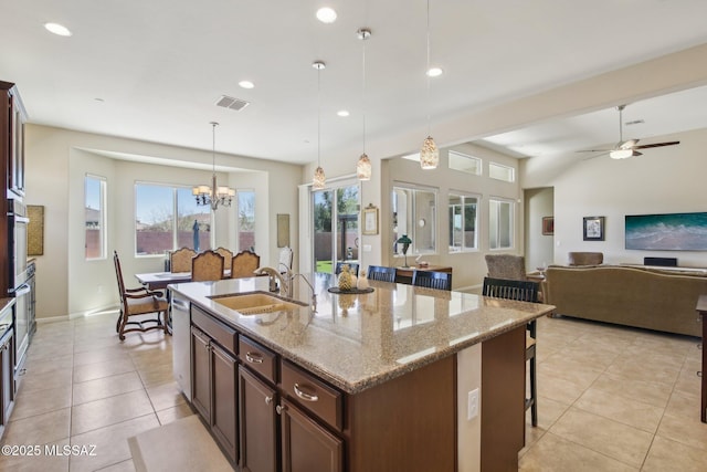 kitchen featuring visible vents, decorative light fixtures, a sink, a kitchen breakfast bar, and light tile patterned flooring