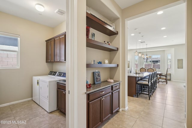 washroom featuring built in features, light tile patterned floors, separate washer and dryer, visible vents, and cabinet space