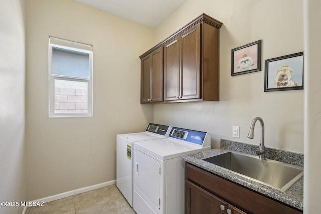 laundry room featuring light tile patterned flooring, a sink, baseboards, cabinet space, and washer and clothes dryer