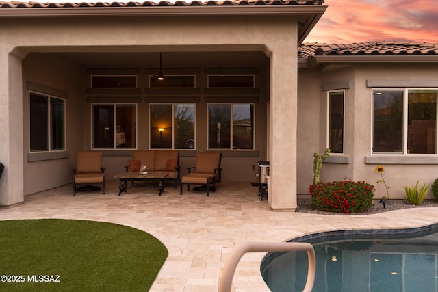 rear view of property featuring a patio, an outdoor pool, stucco siding, and a tiled roof