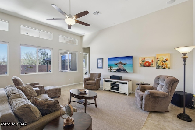 living area with visible vents, baseboards, ceiling fan, a towering ceiling, and light tile patterned flooring
